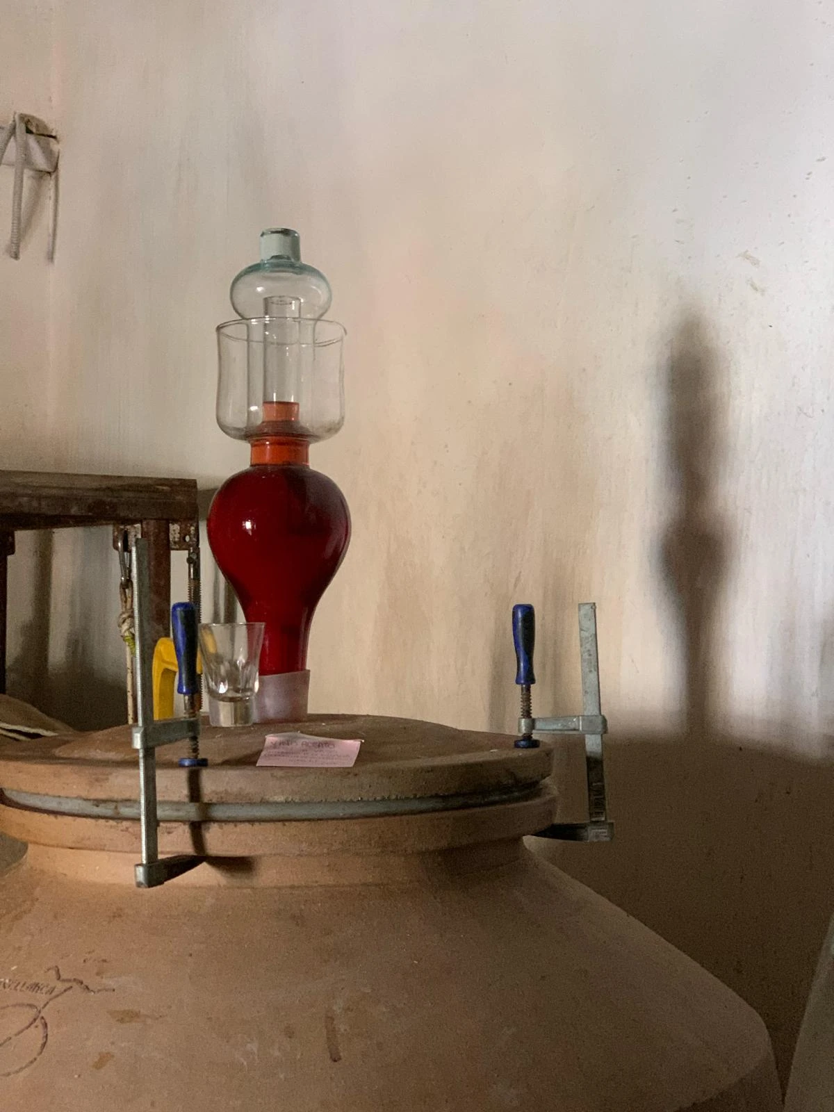 Vino rosso nel gorgogliatore sopra un'anfora di terracotta